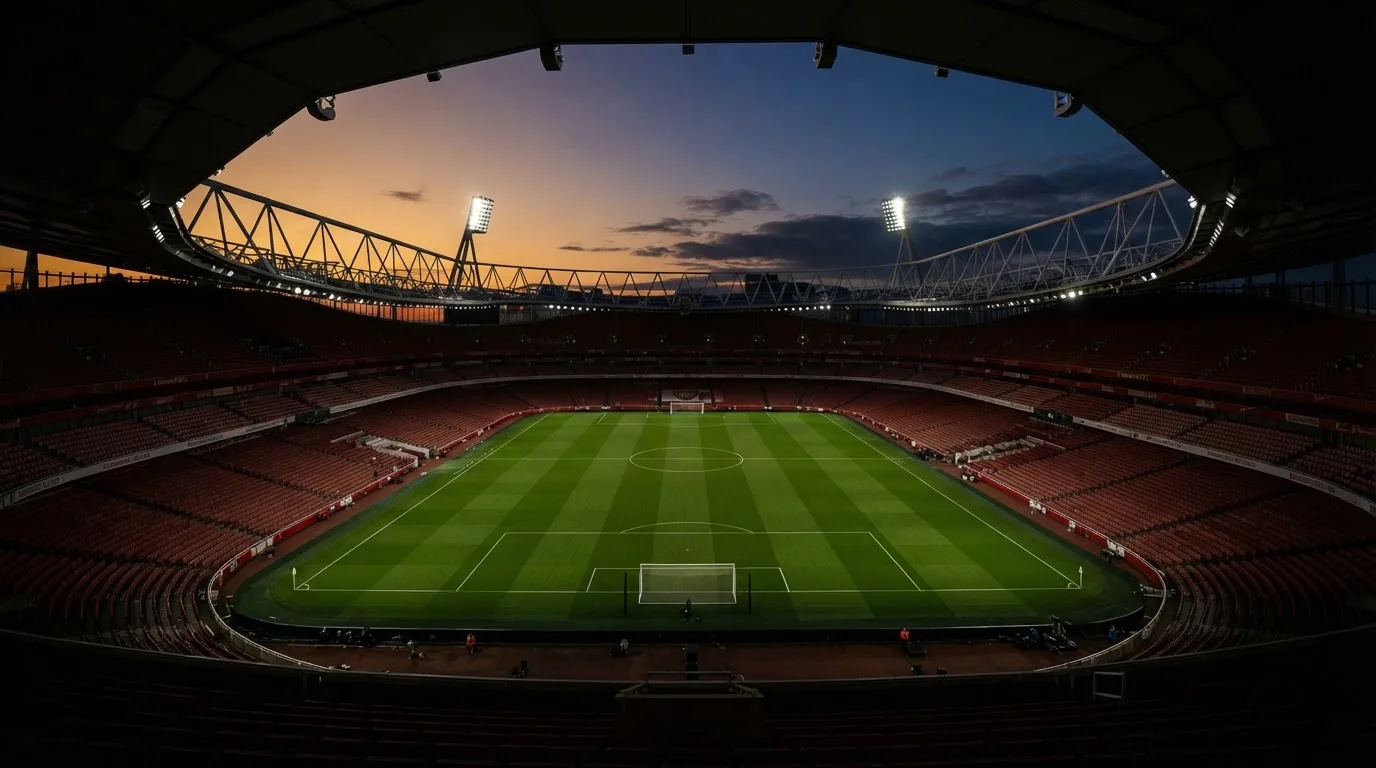 An empty football stadium with floodlight masts at dusk