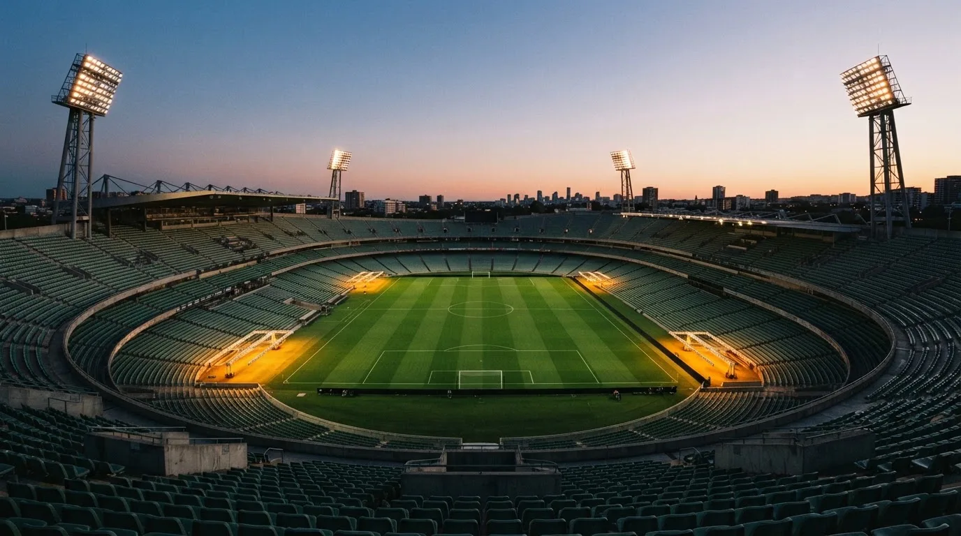 An empty football stadium with floodlight masts at dusk