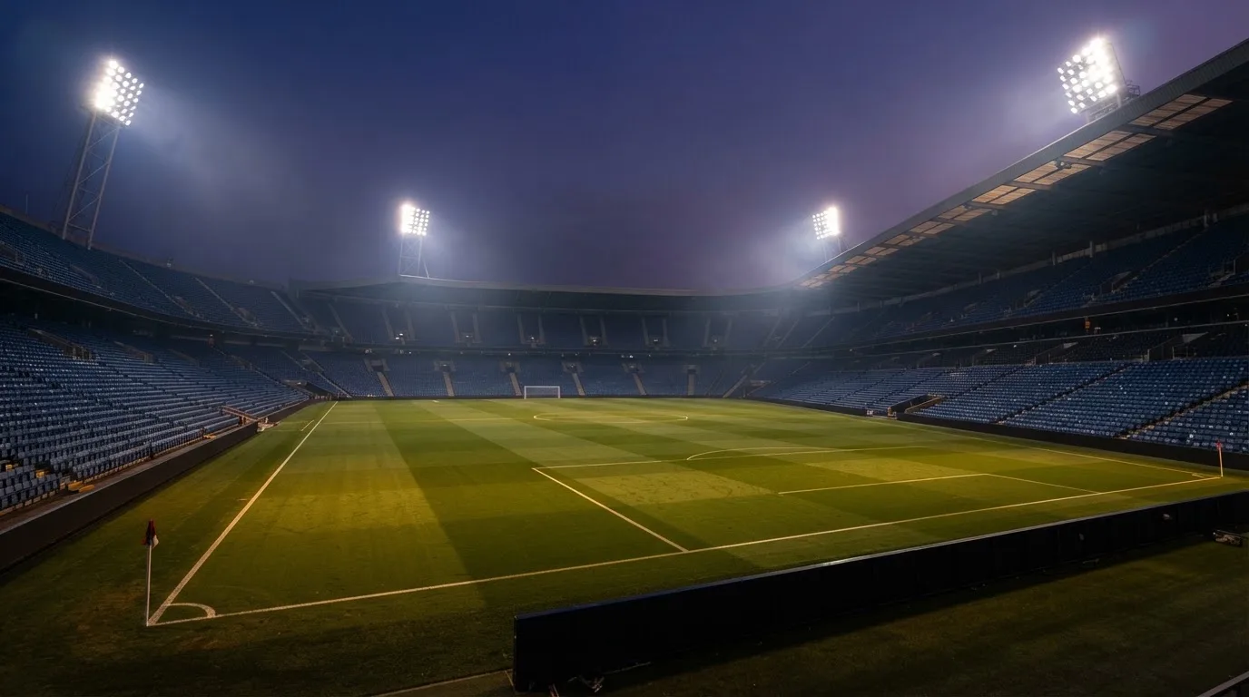 An empty football stadium with floodlight masts at dusk