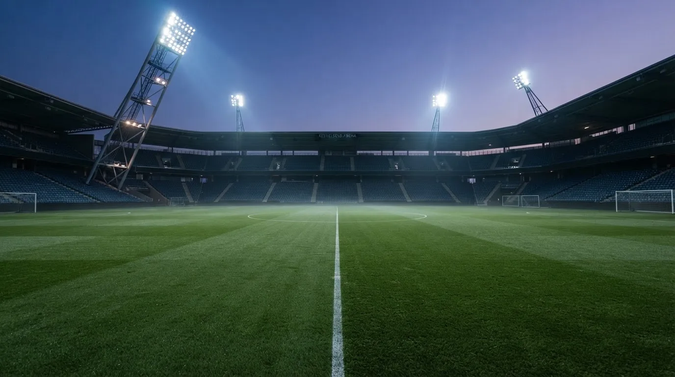 An empty football stadium with floodlight masts at dusk