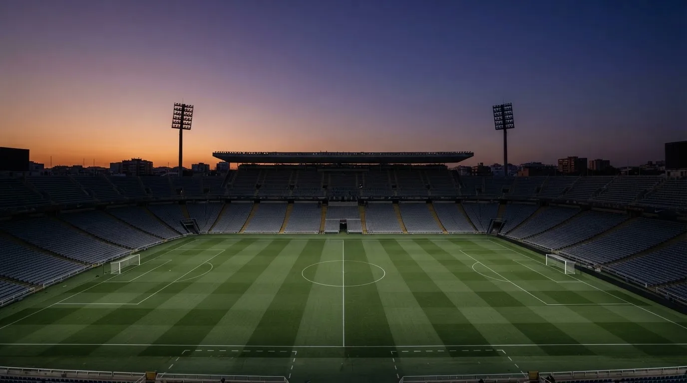 An empty football stadium with floodlight masts at dusk