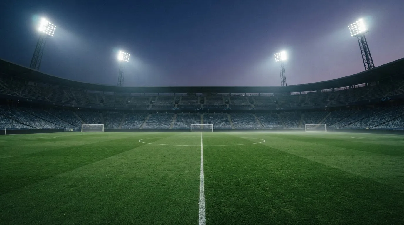 An empty football stadium with floodlight masts at dusk