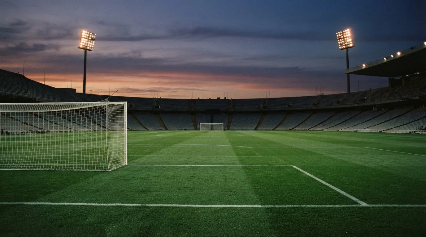 An empty football stadium with floodlight masts at dusk