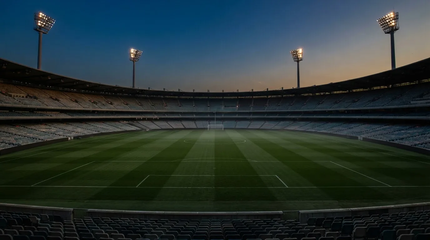 An empty football stadium with floodlight masts at dusk
