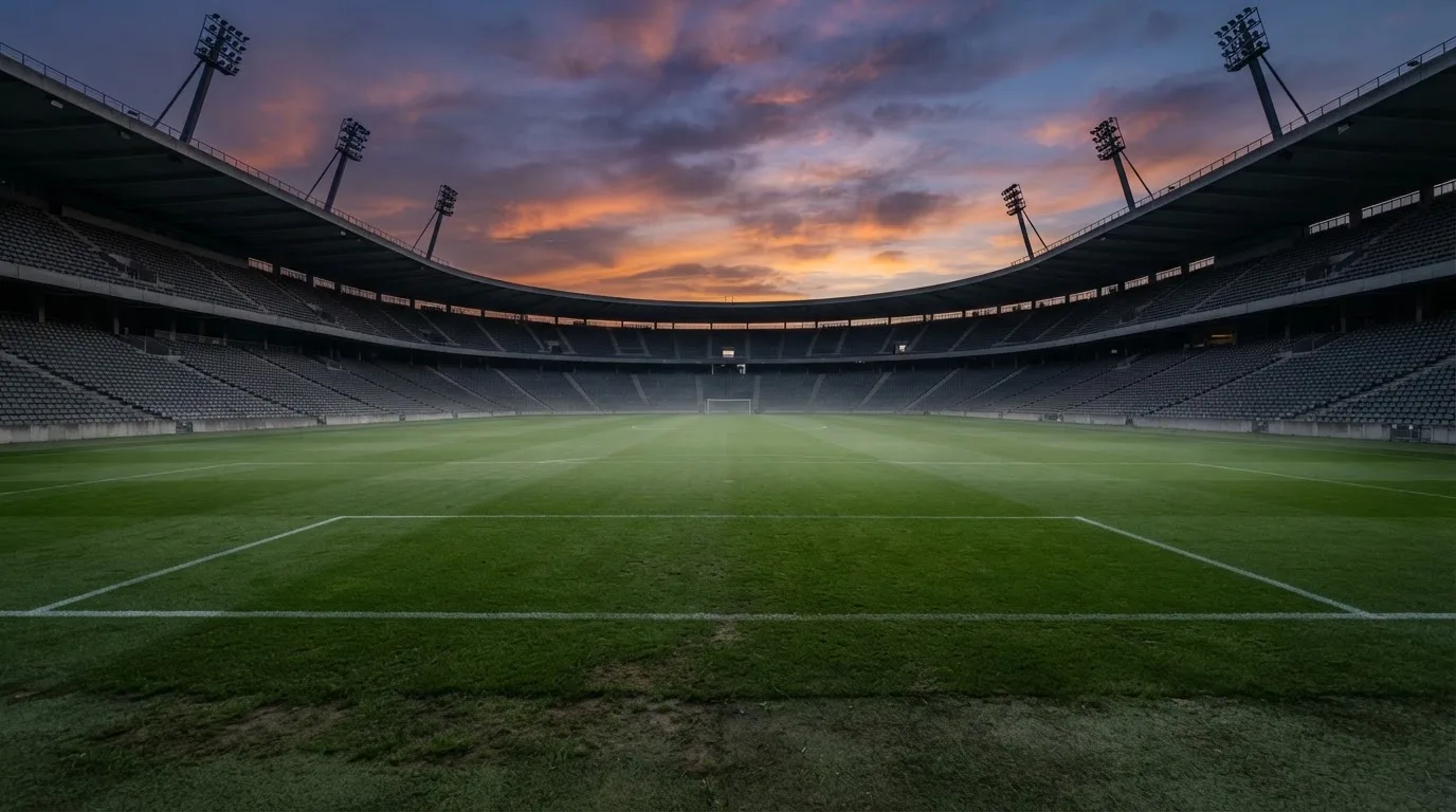 An empty football stadium with floodlight masts at dusk