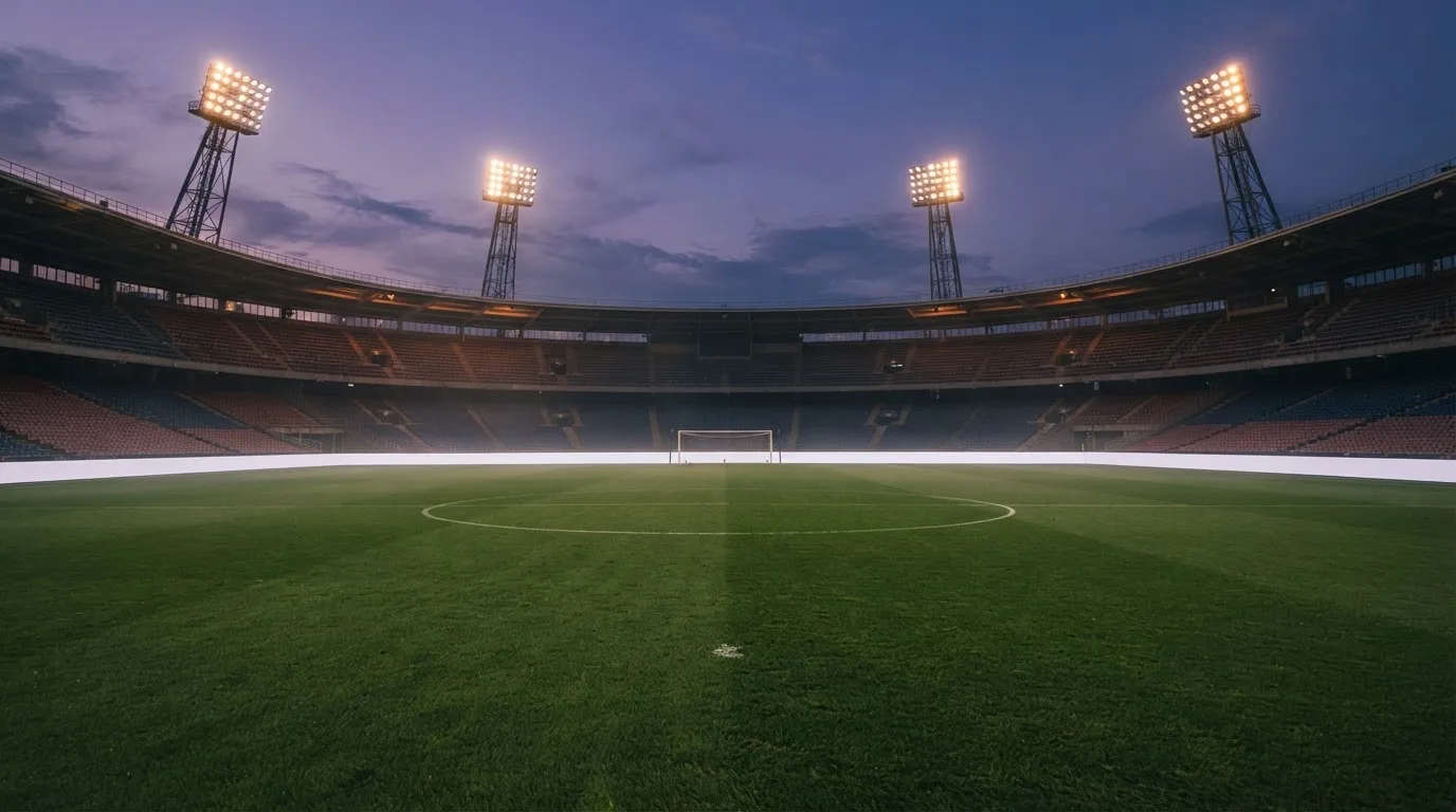 An empty football stadium with floodlight masts at dusk