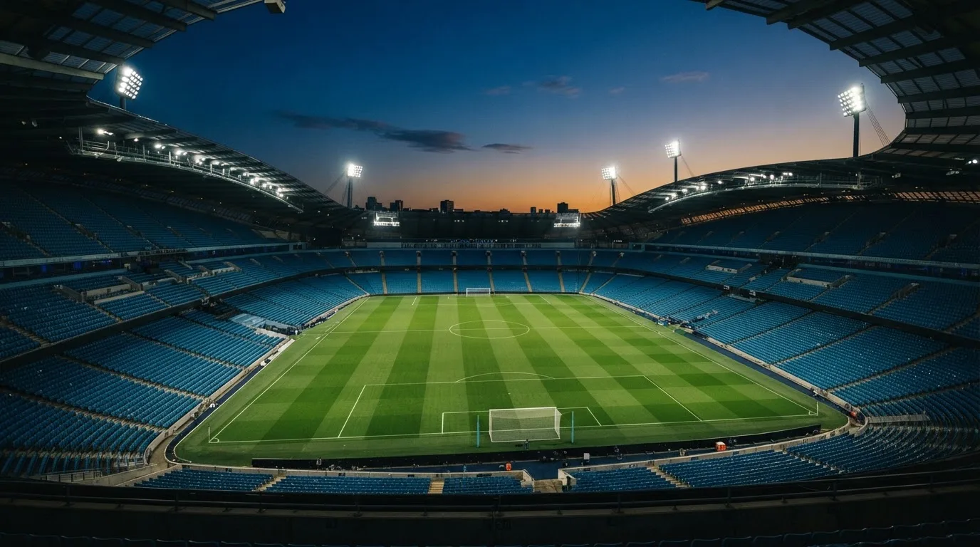 An empty football stadium with floodlight masts at dusk