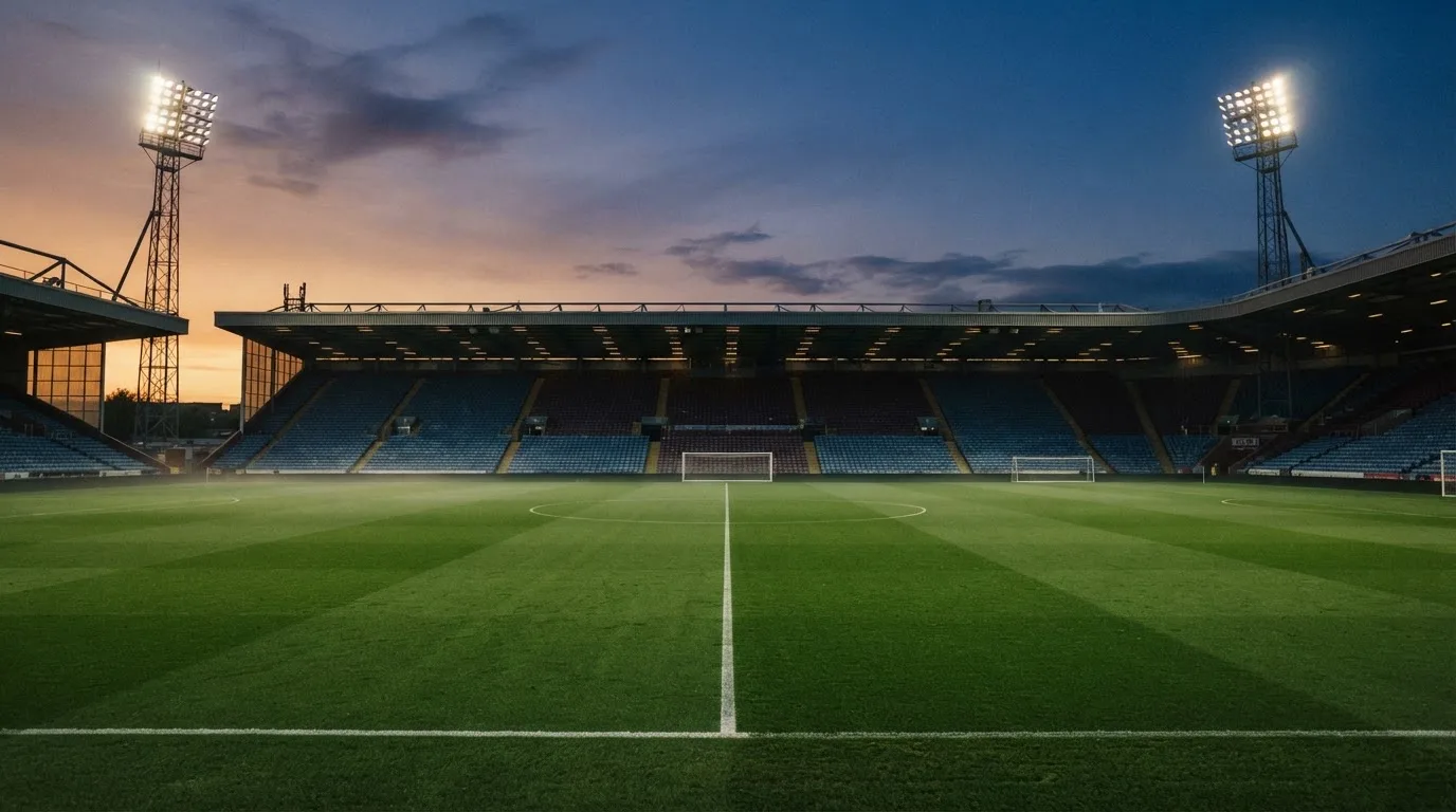 An empty football stadium with floodlight masts at dusk