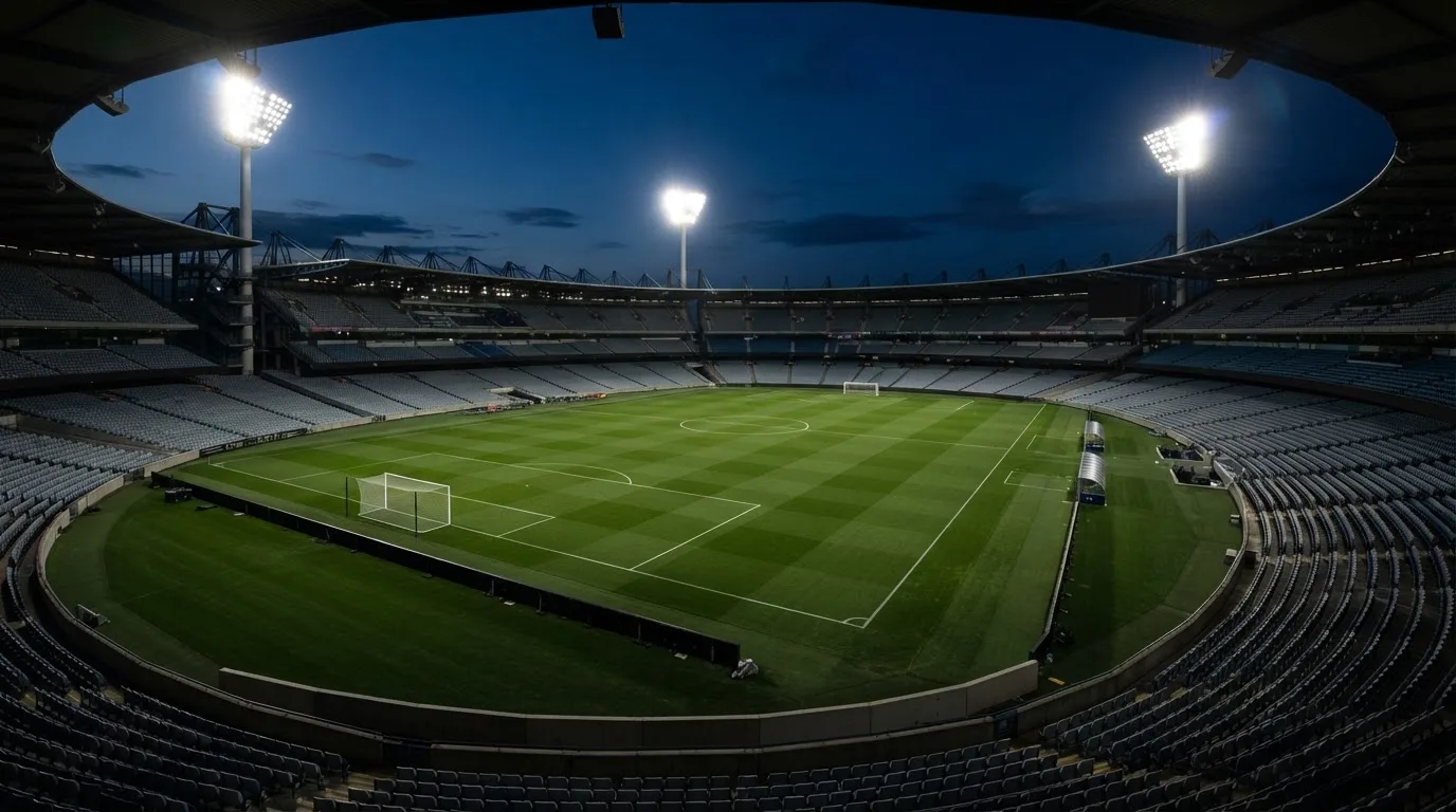An empty football stadium with floodlight masts at dusk