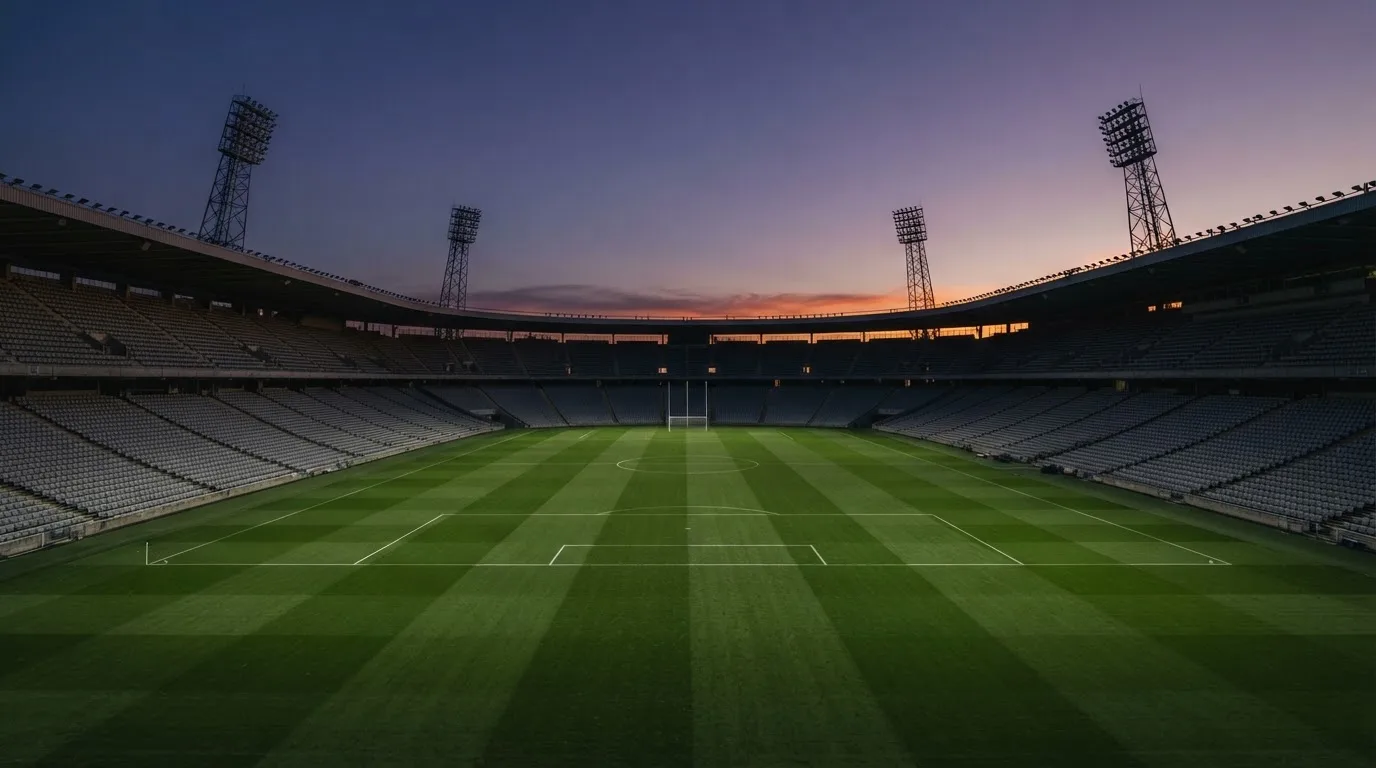 An empty football stadium with floodlight masts at dusk