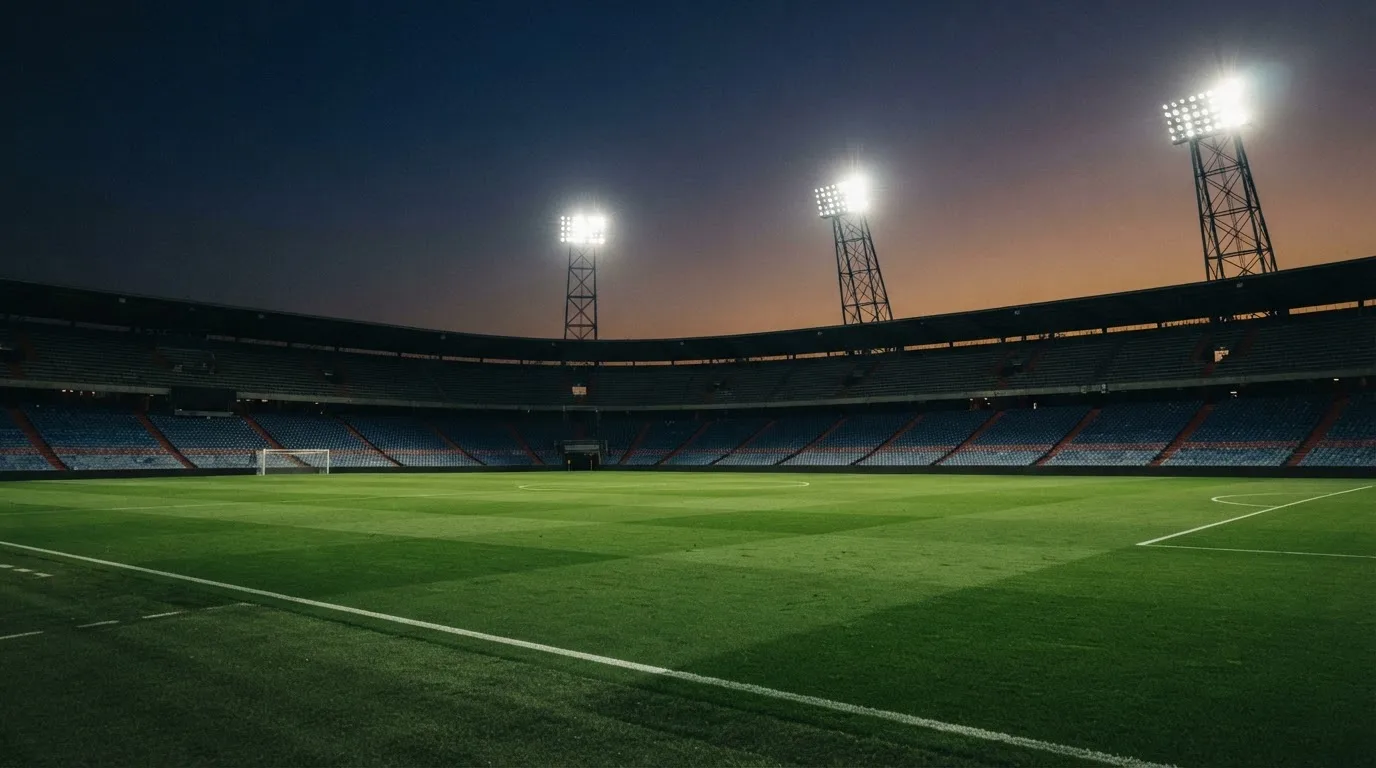 An empty football stadium with floodlight masts at dusk