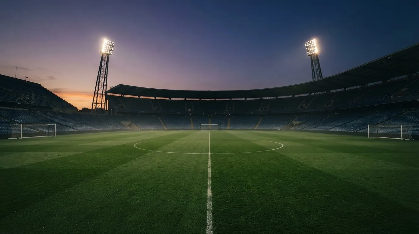 An empty football stadium with floodlight masts at dusk