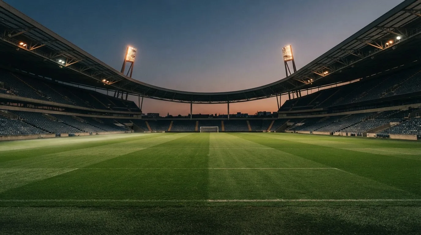 An empty football stadium with floodlight masts at dusk