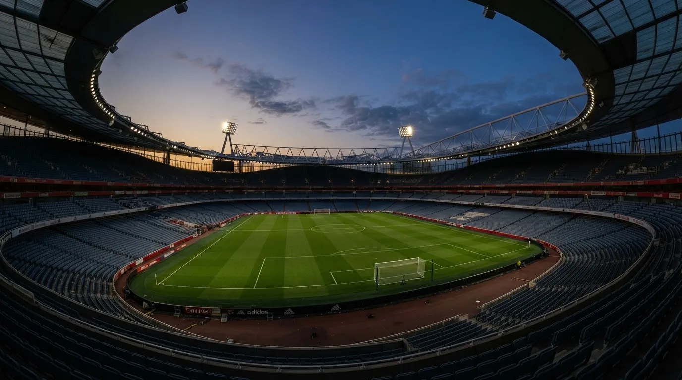 An empty football stadium with floodlight masts at dusk