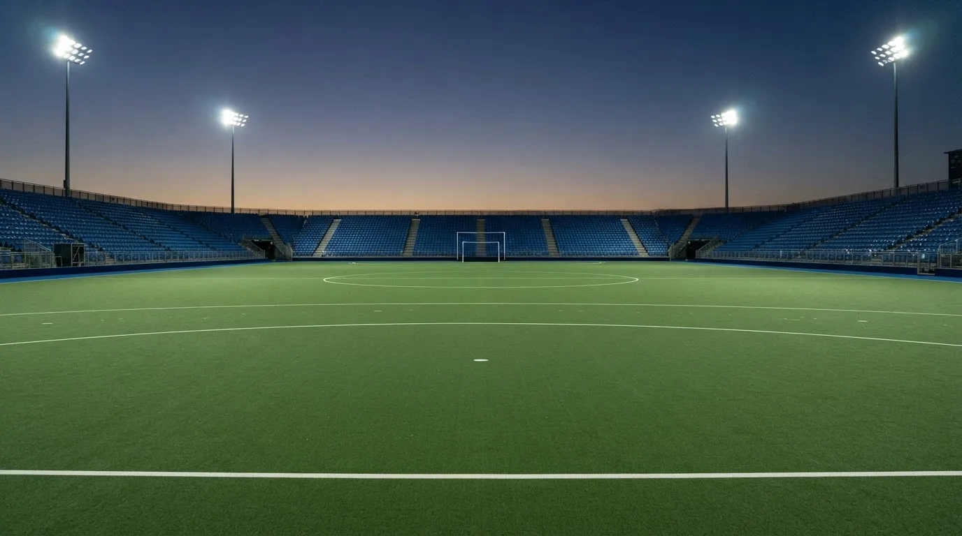 An empty football stadium with floodlight masts at dusk
