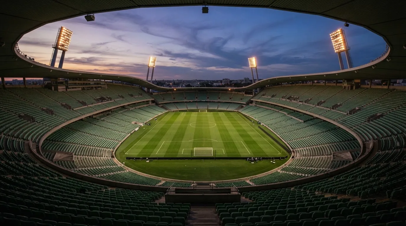 An empty football stadium with floodlight masts at dusk