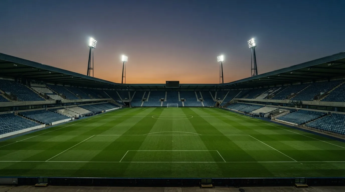 An empty football stadium with floodlight masts at dusk
