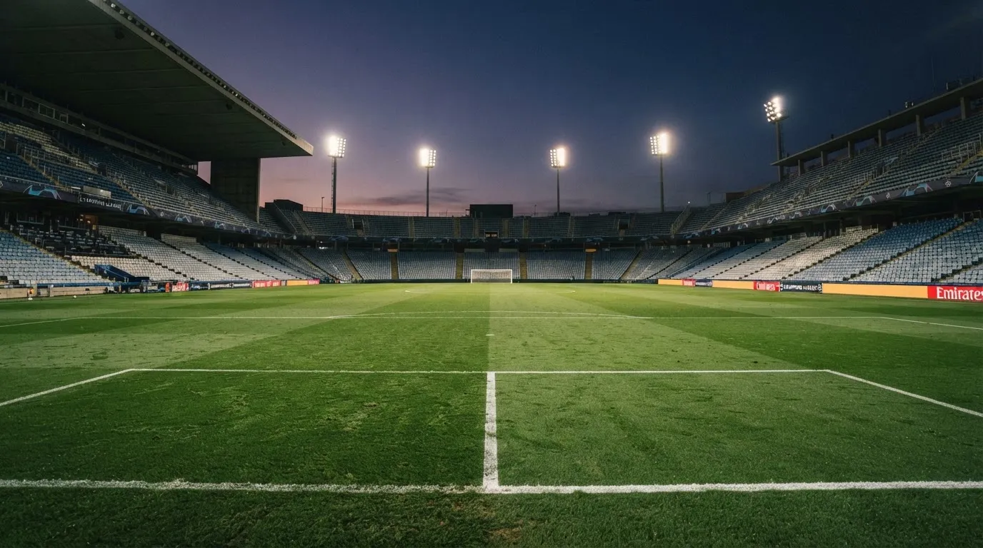 An empty football stadium with floodlight masts at dusk