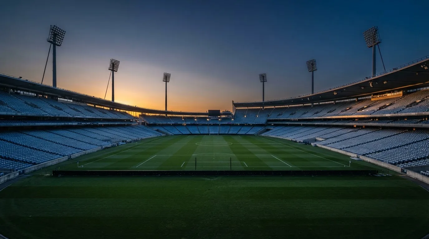 An empty football stadium with floodlight masts at dusk