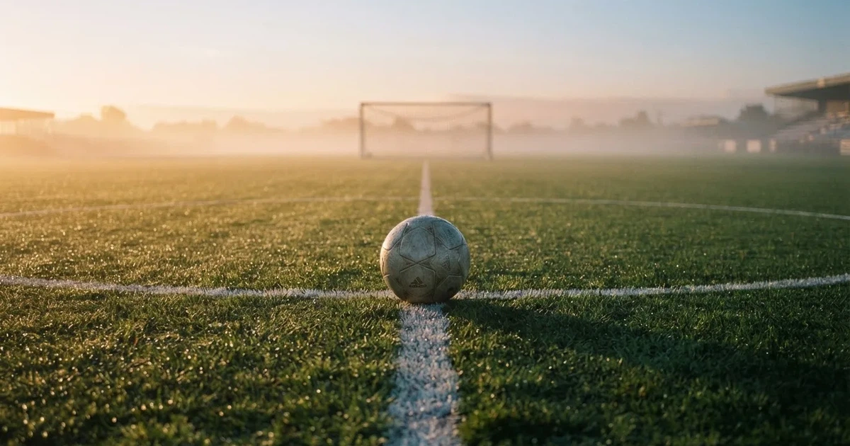 A ball on the centre spot of a grass pitch in morning light