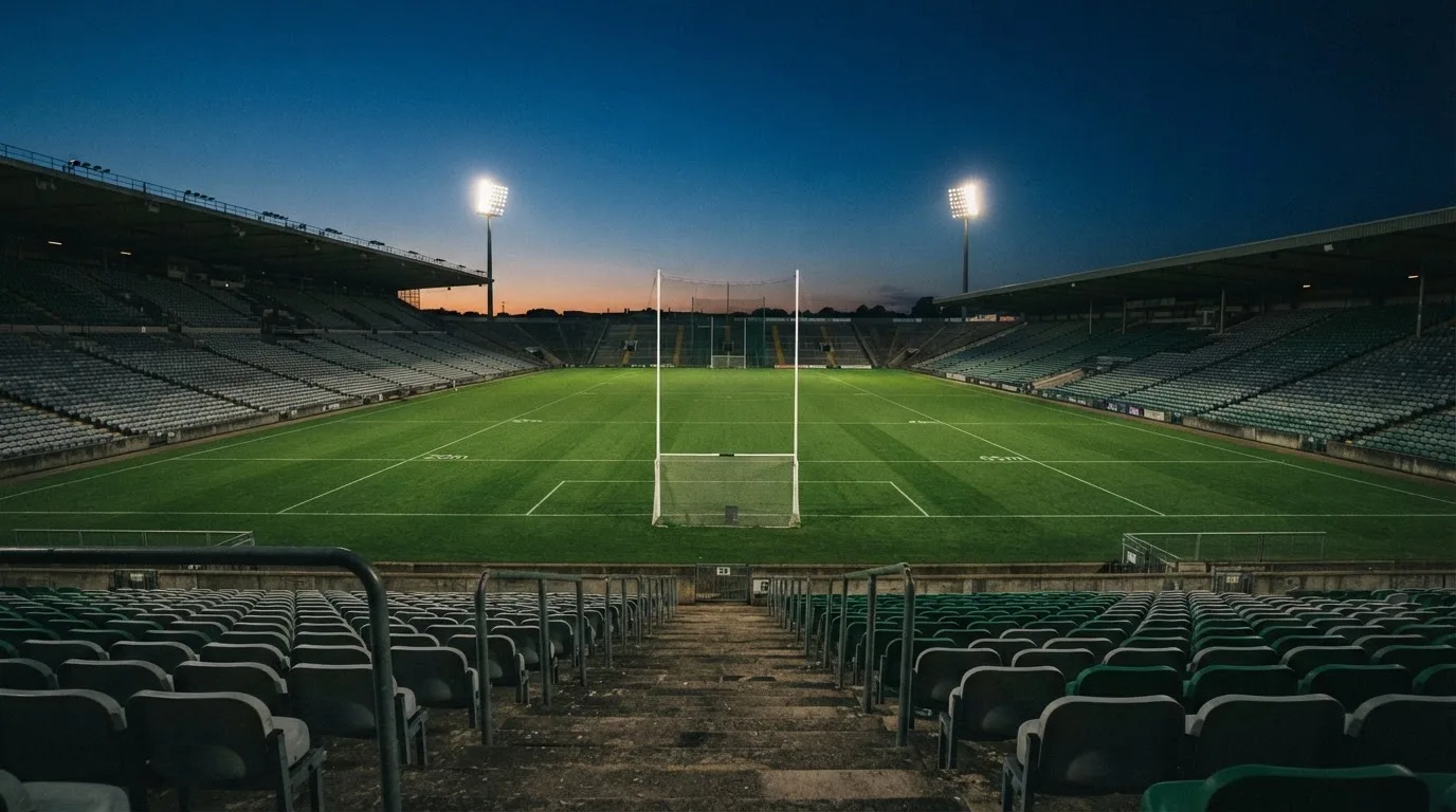 An empty football stadium with floodlight masts at dusk