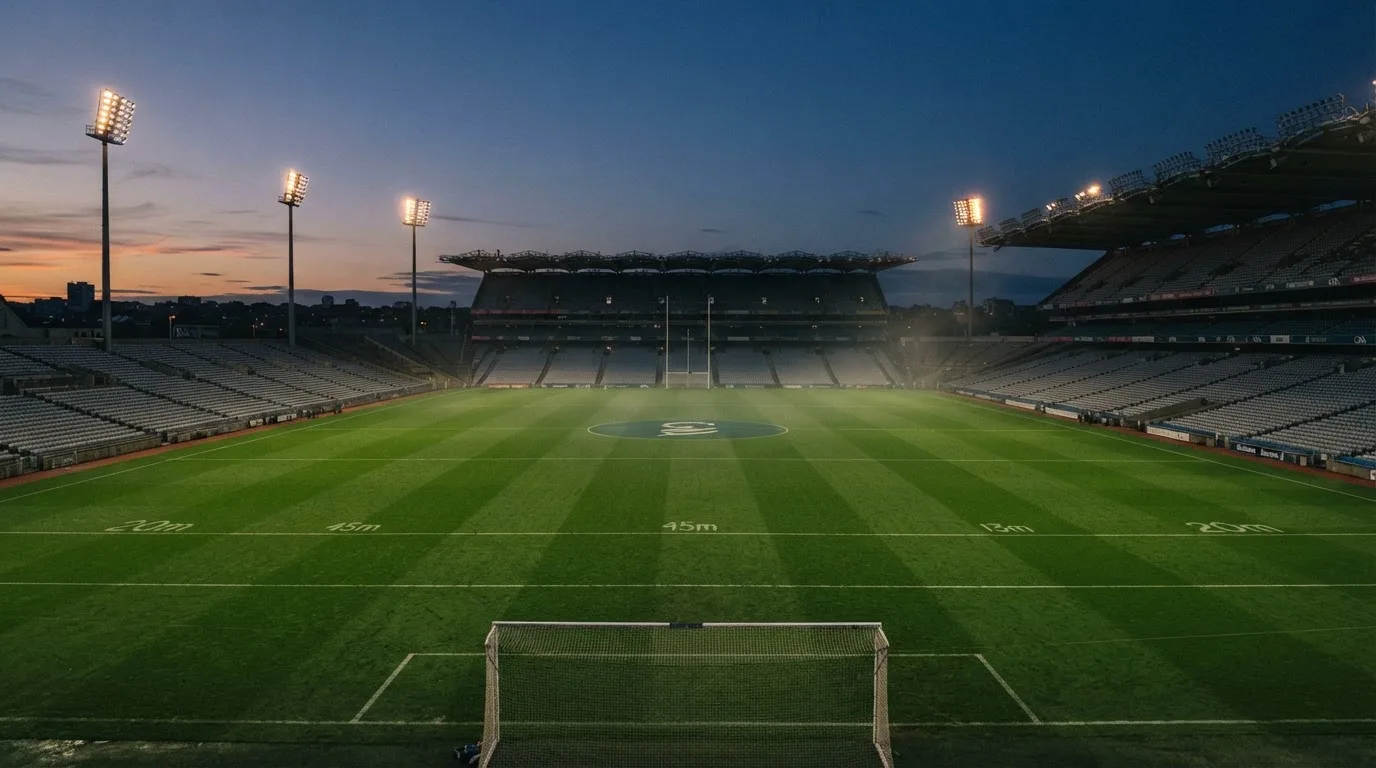 An empty football stadium with floodlight masts at dusk