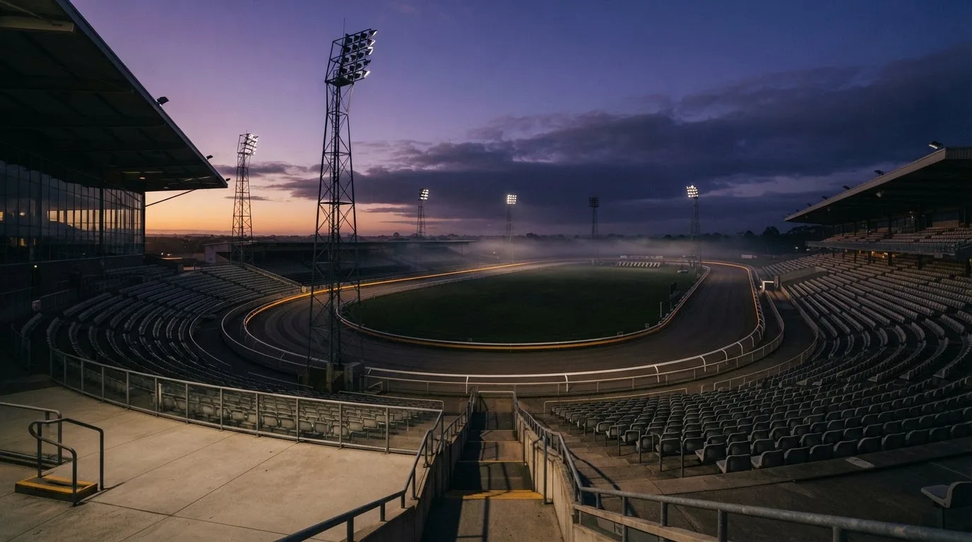 An empty football stadium with floodlight masts at dusk