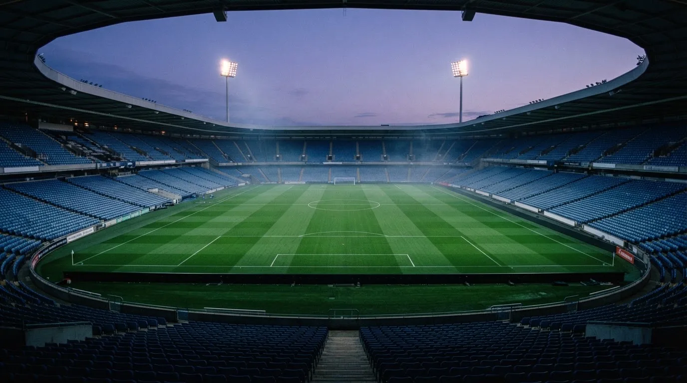 An empty football stadium with floodlight masts at dusk