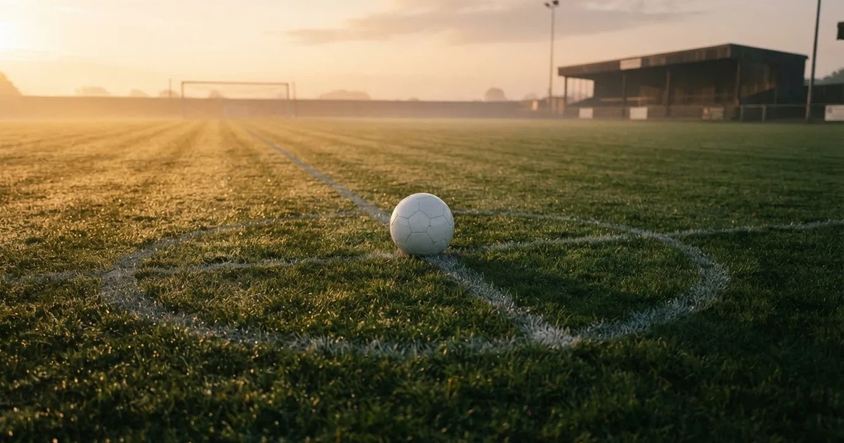 A ball on the centre spot of a grass pitch in morning light