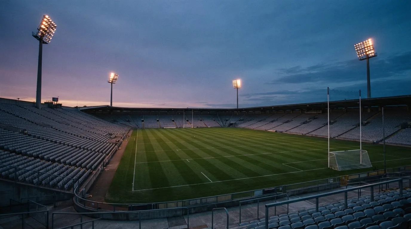 An empty football stadium with floodlight masts at dusk