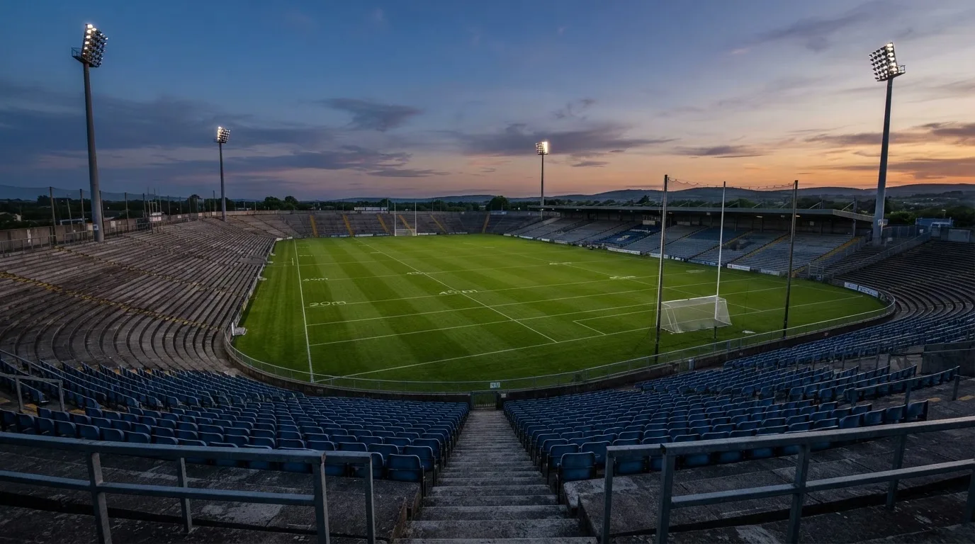 An empty football stadium with floodlight masts at dusk
