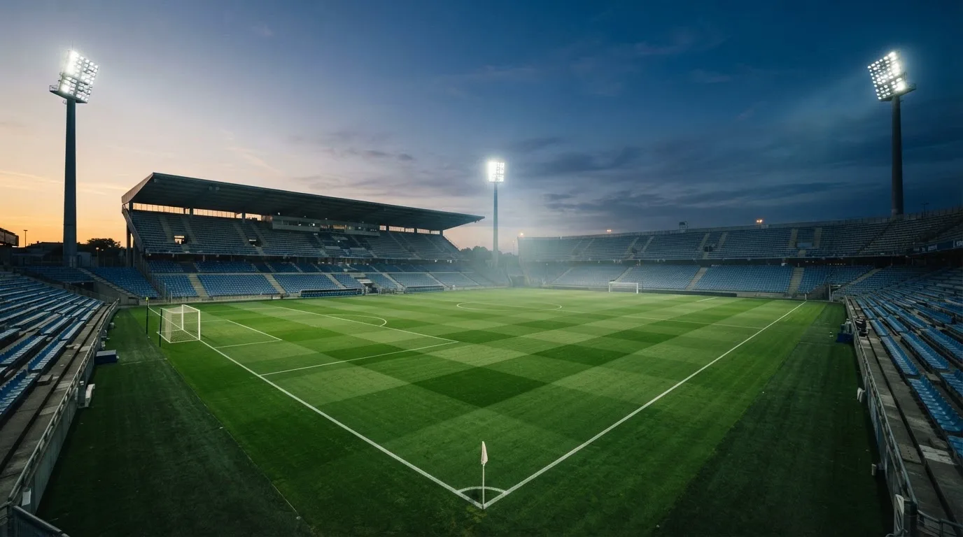 An empty football stadium with floodlight masts at dusk
