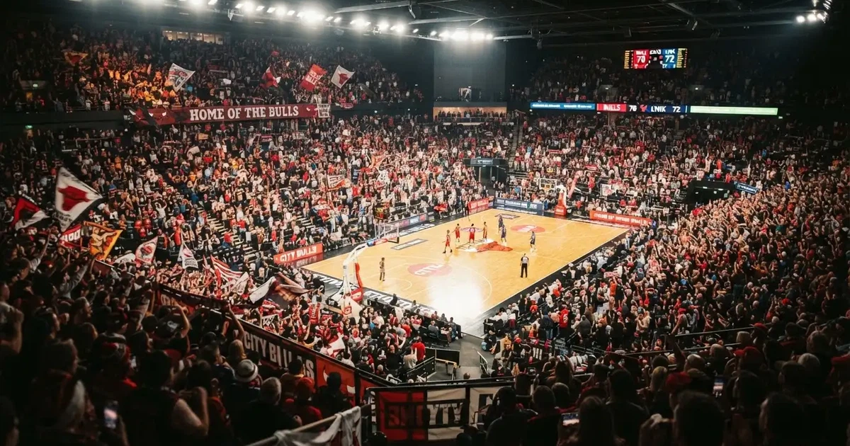A packed sports hall under floodlights photographed from a long way off