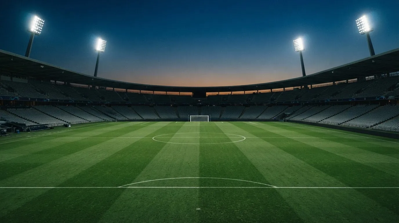 An empty football stadium with floodlight masts at dusk