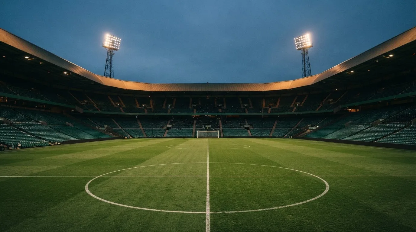 An empty football stadium with floodlight masts at dusk