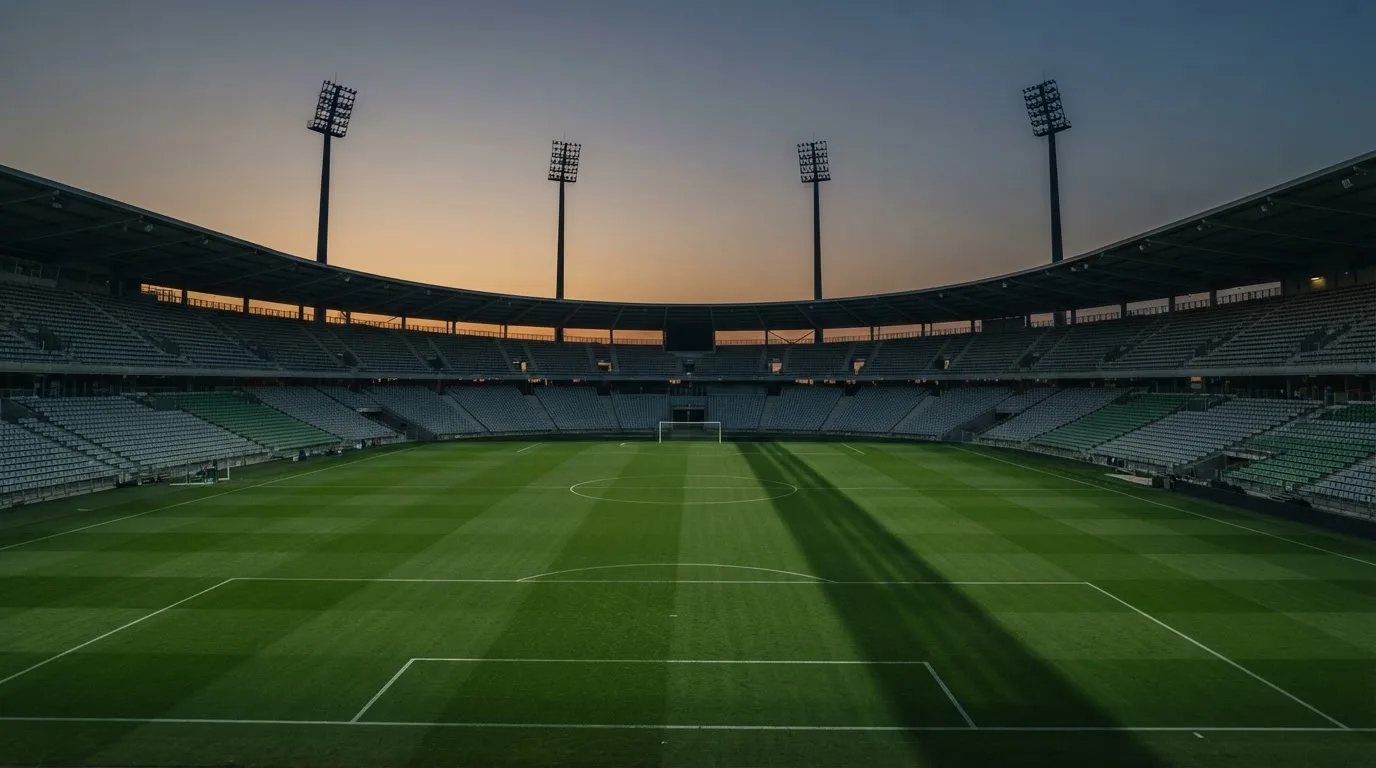 An empty football stadium with floodlight masts at dusk