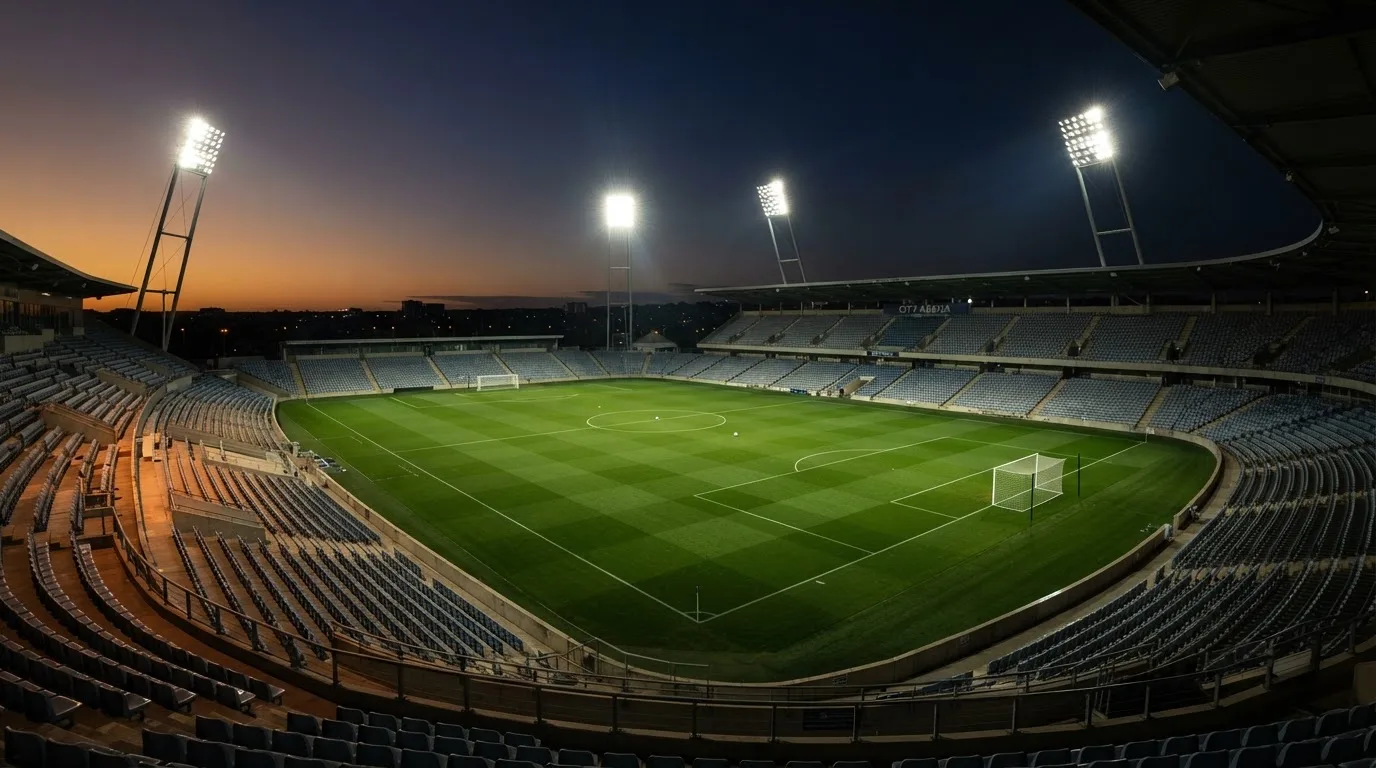 An empty football stadium with floodlight masts at dusk