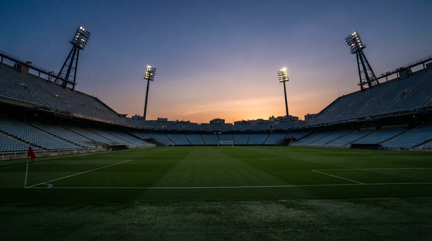 An empty football stadium with floodlight masts at dusk