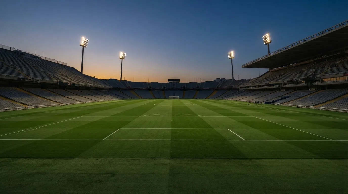 An empty football stadium with floodlight masts at dusk
