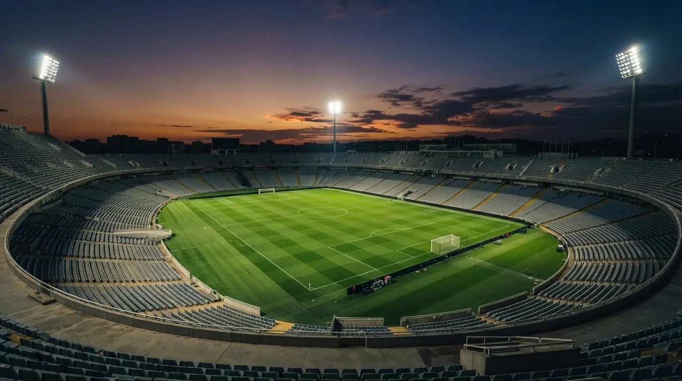 An empty football stadium with floodlight masts at dusk