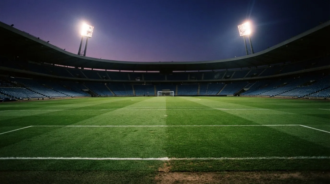 An empty football stadium with floodlight masts at dusk