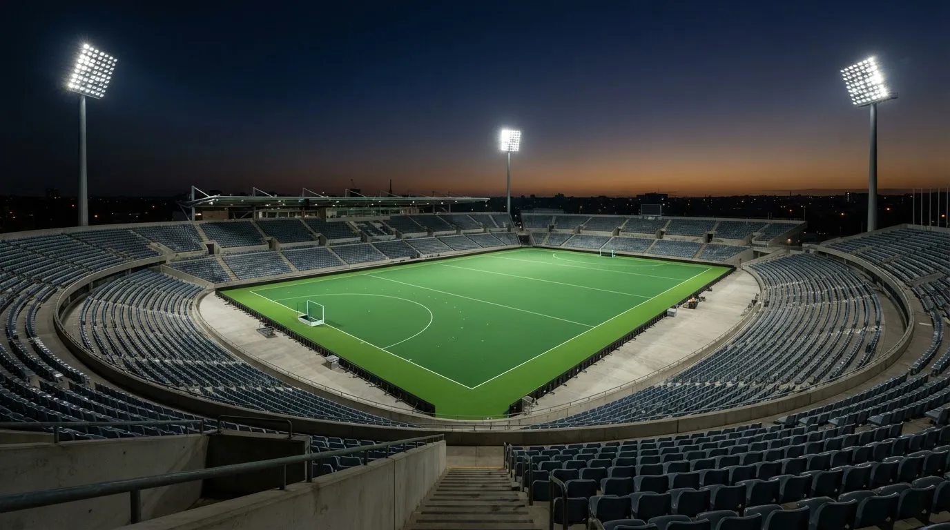 An empty football stadium with floodlight masts at dusk