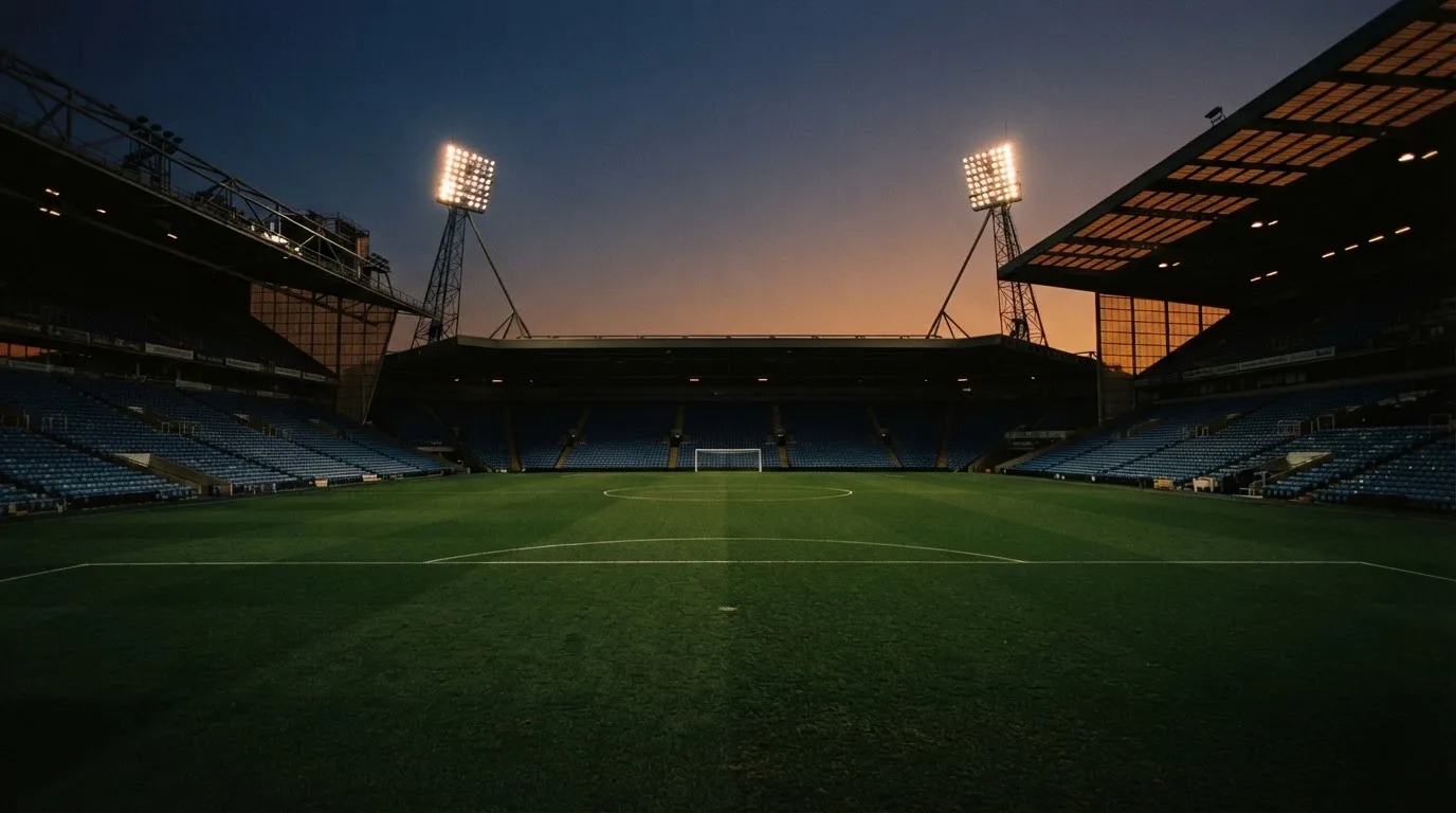 An empty football stadium with floodlight masts at dusk