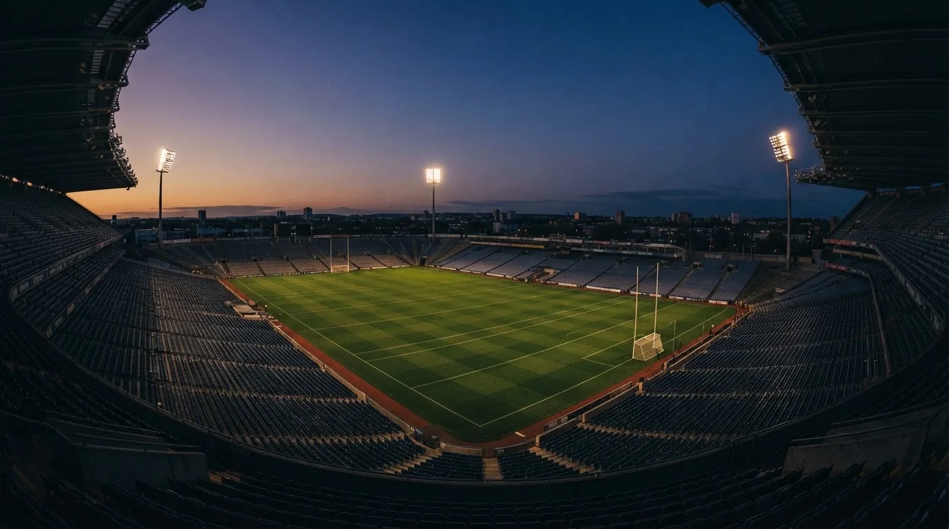 An empty football stadium with floodlight masts at dusk