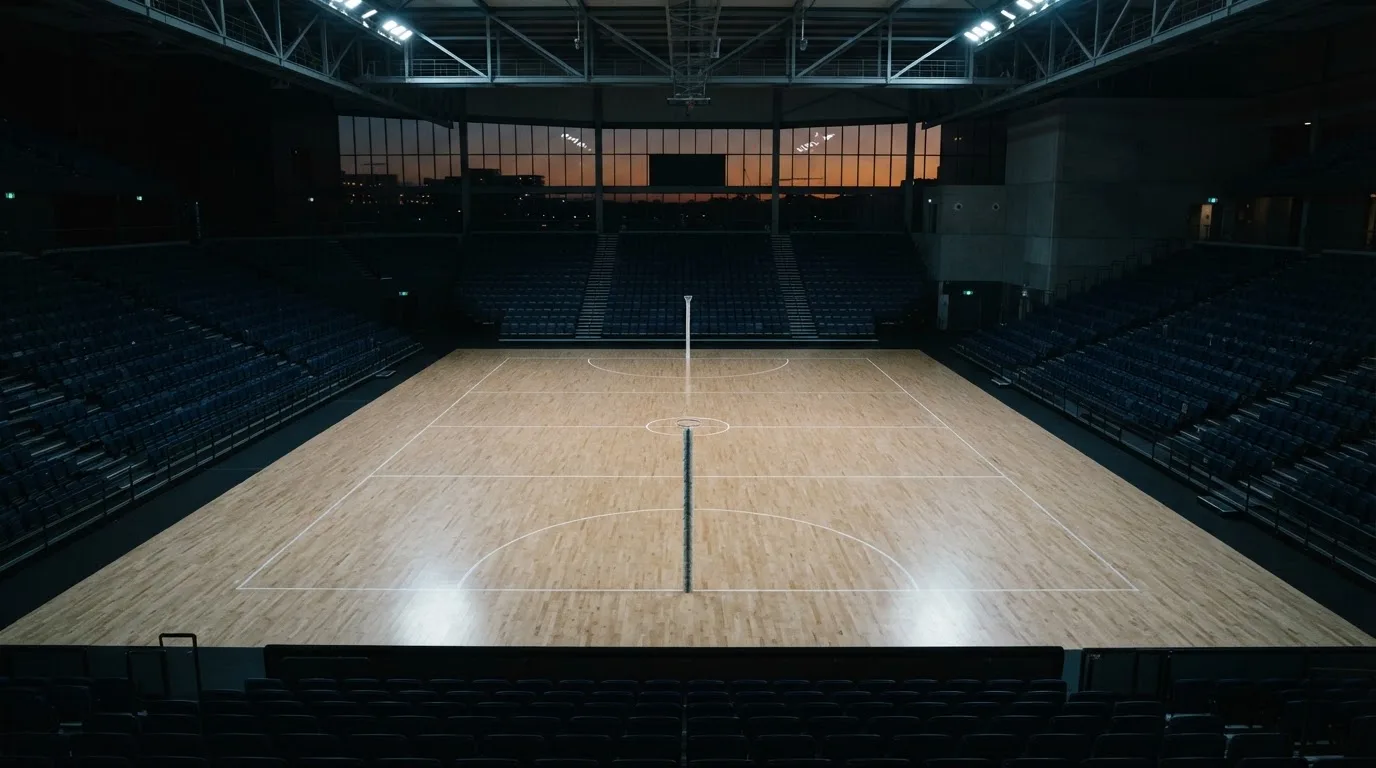 An empty football stadium with floodlight masts at dusk