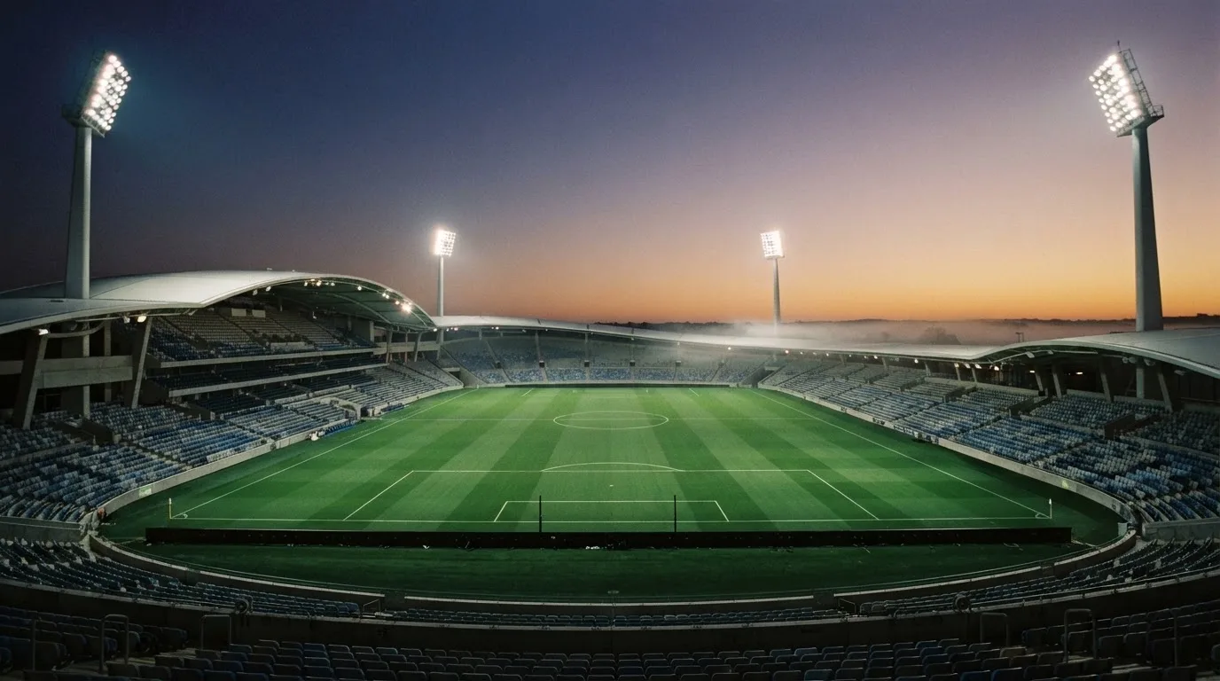 An empty football stadium with floodlight masts at dusk