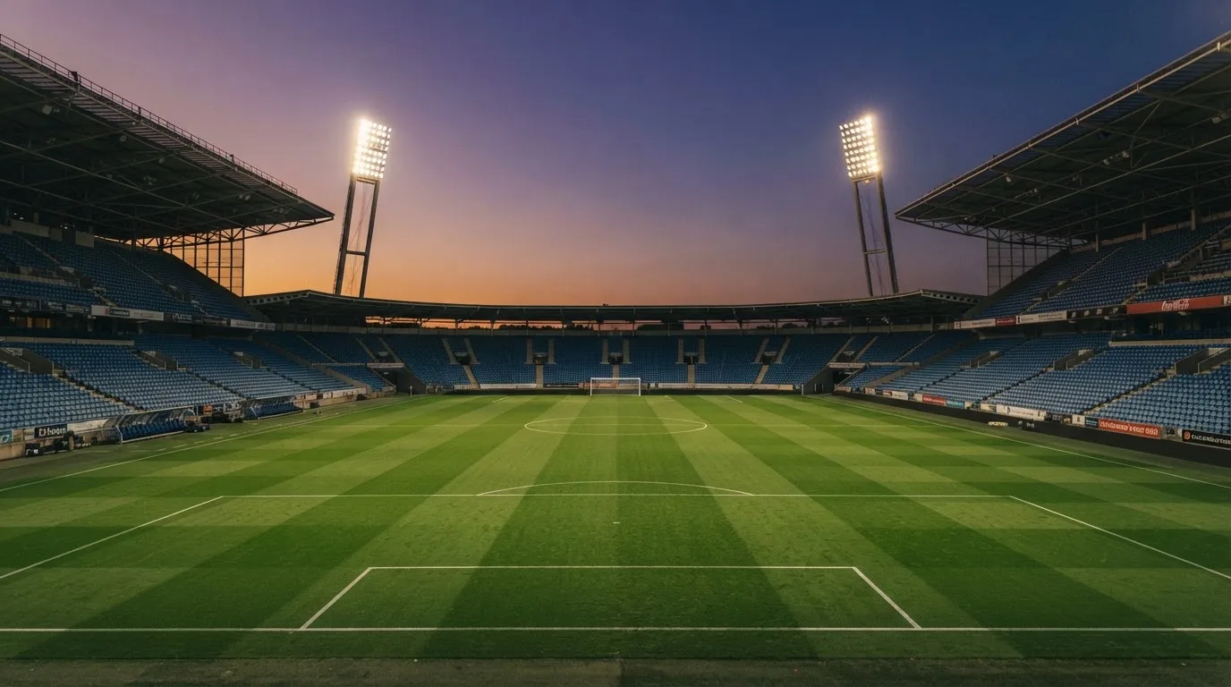 An empty football stadium with floodlight masts at dusk