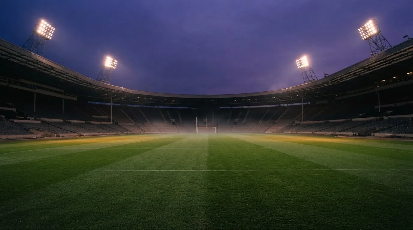 An empty football stadium with floodlight masts at dusk