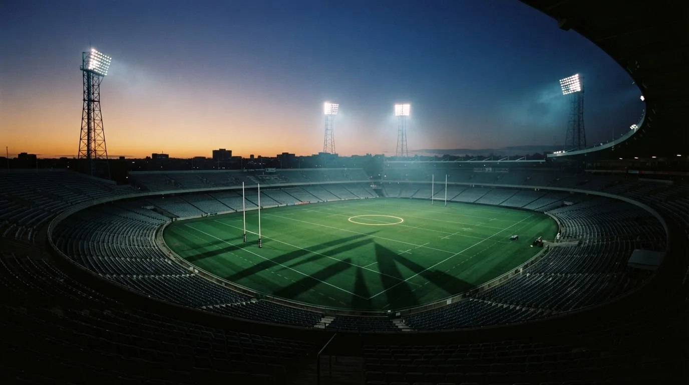 An empty football stadium with floodlight masts at dusk