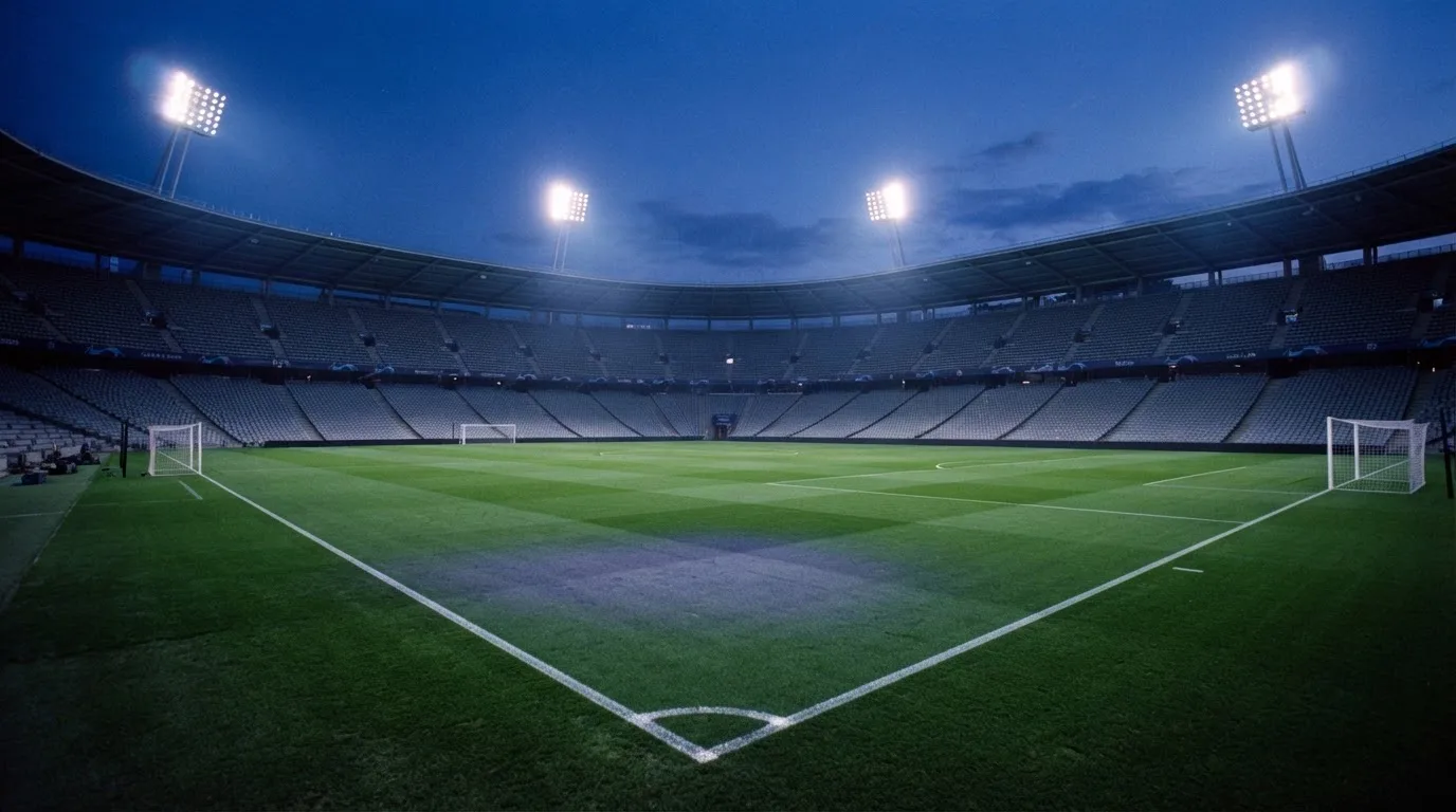An empty football stadium with floodlight masts at dusk